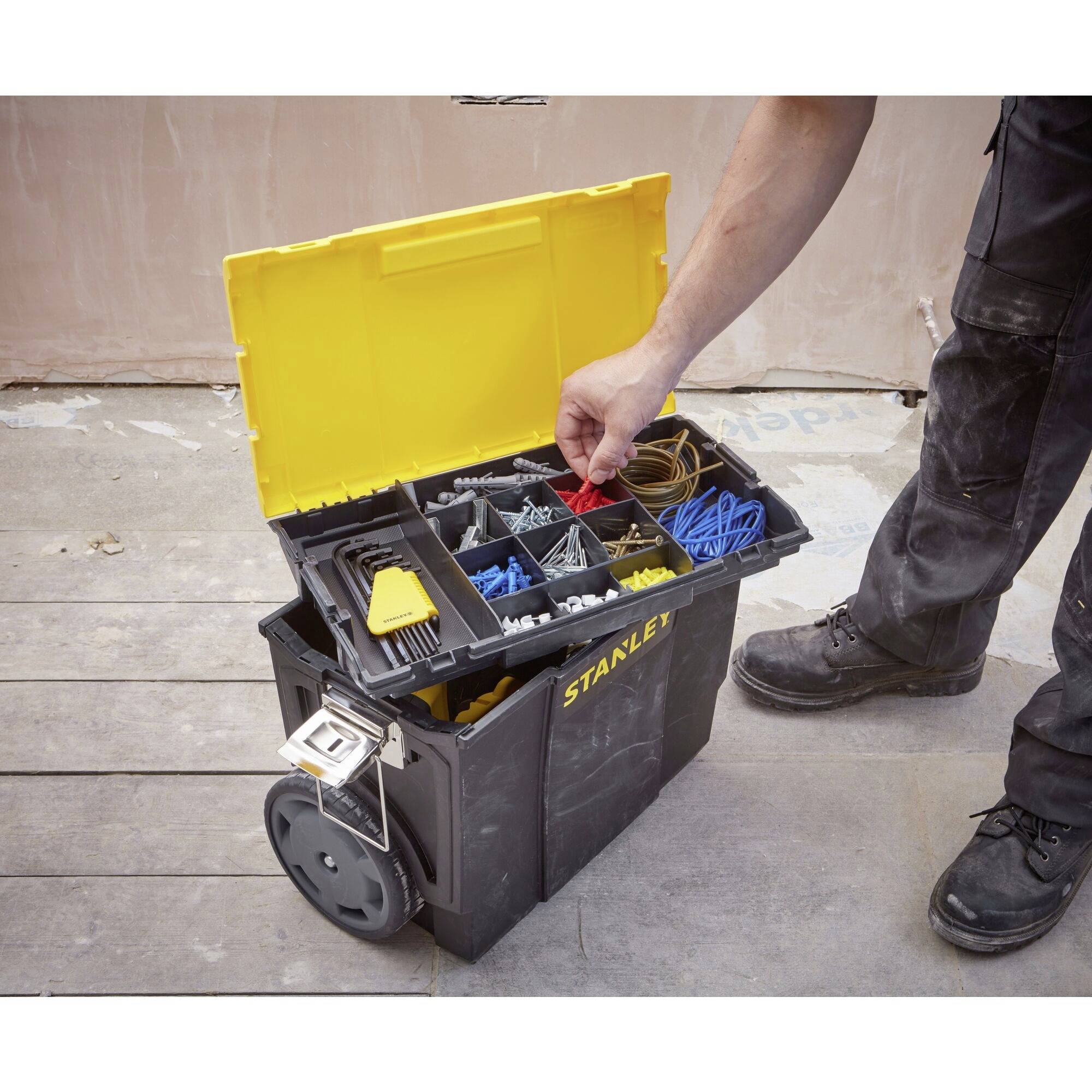 An open toolbox with various cables and accessory parts. A person is holding up a red cable.