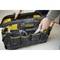A hand reaches into an opened black tool bag with yellow accents and multiple compartments. The bag contains various tools.