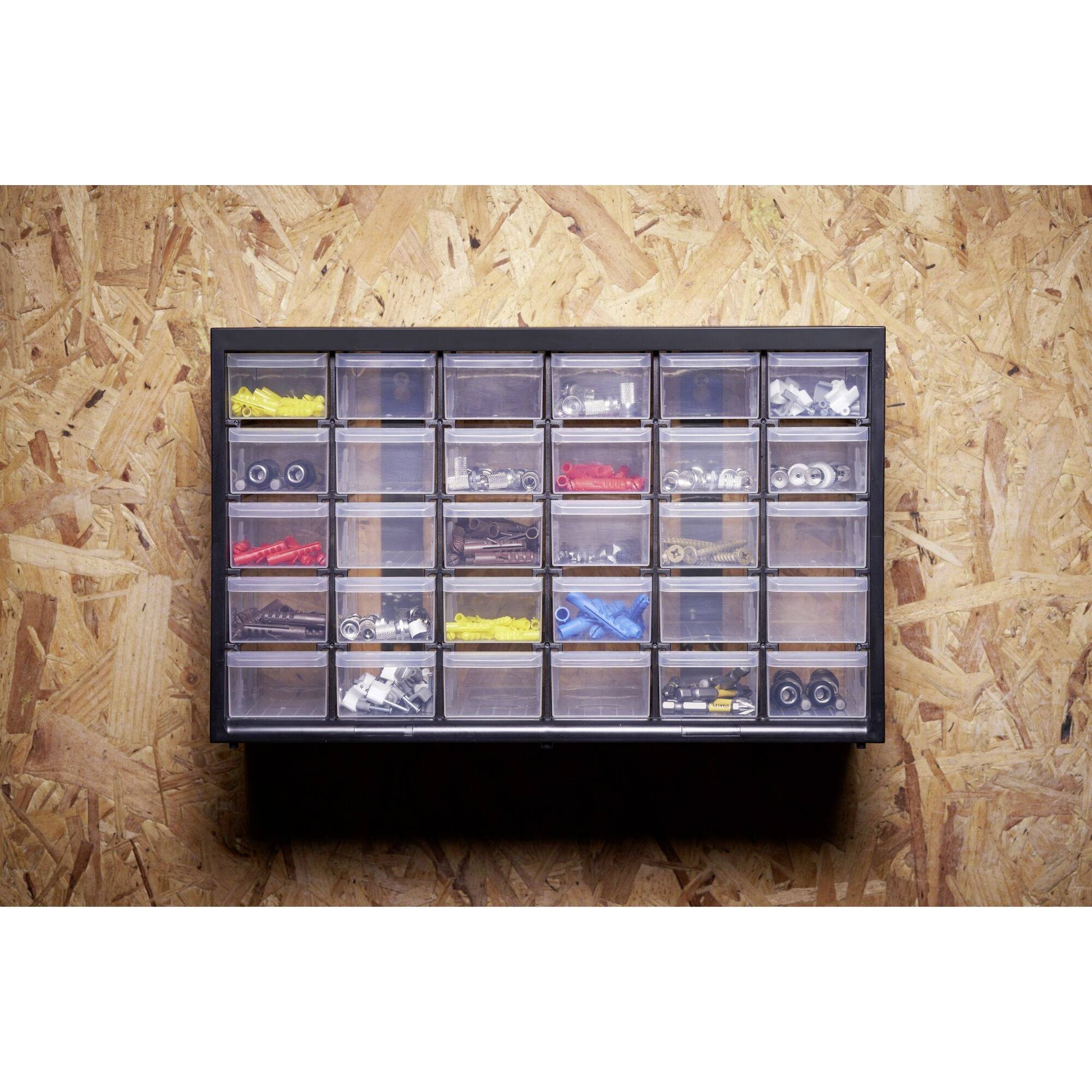 A sorted drawer cabinet with small tools and spare parts, mounted on a chipboard wall.