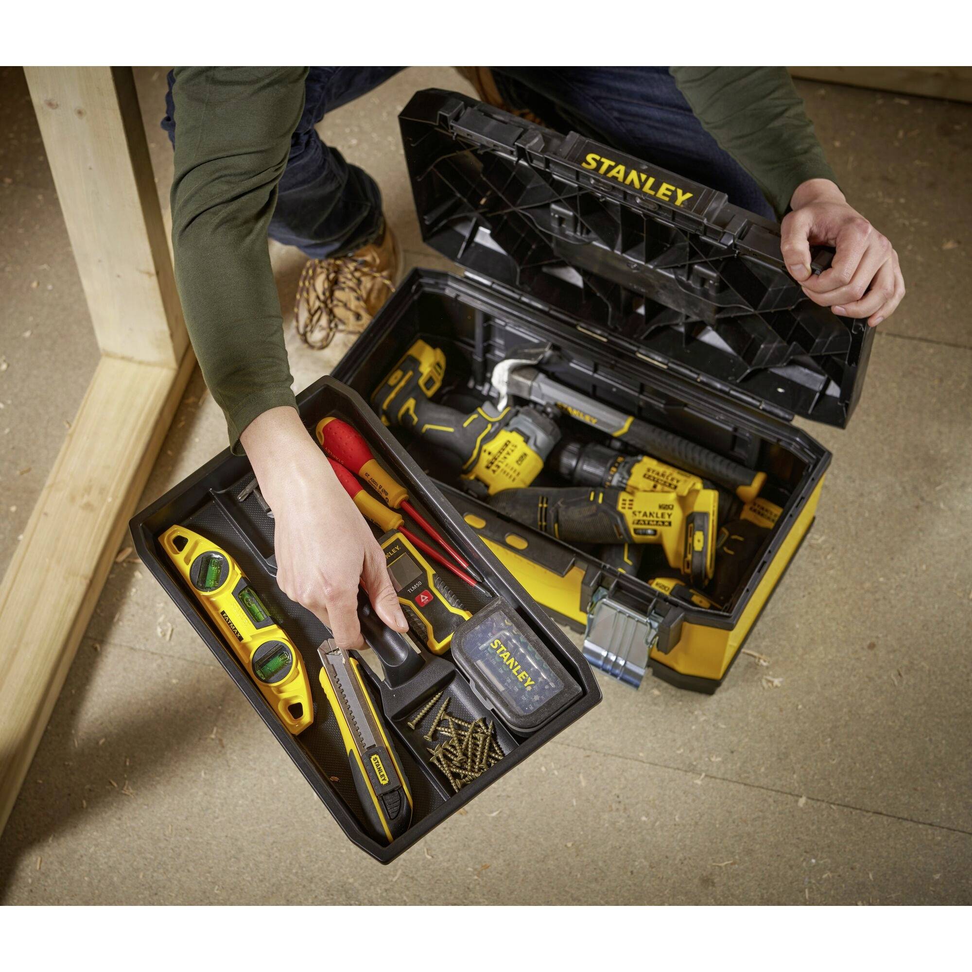 A person is holding a tool set with a screwdriver, spirit level, screws, a drill, and other tools in a case.
