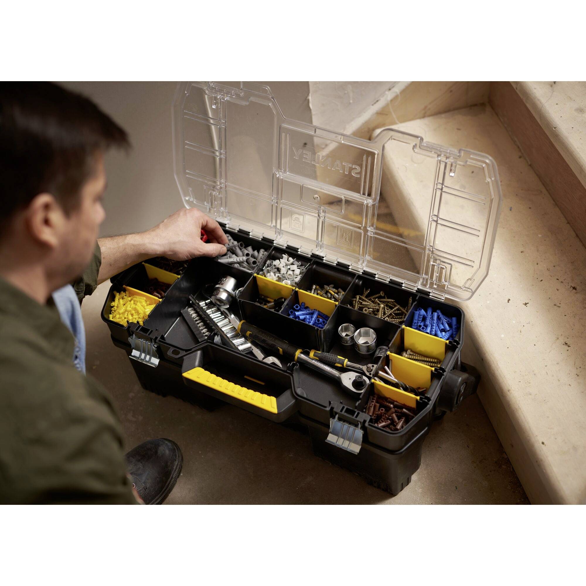 A person opens a black toolbox with visible compartments containing screws, nuts, and other tool parts.