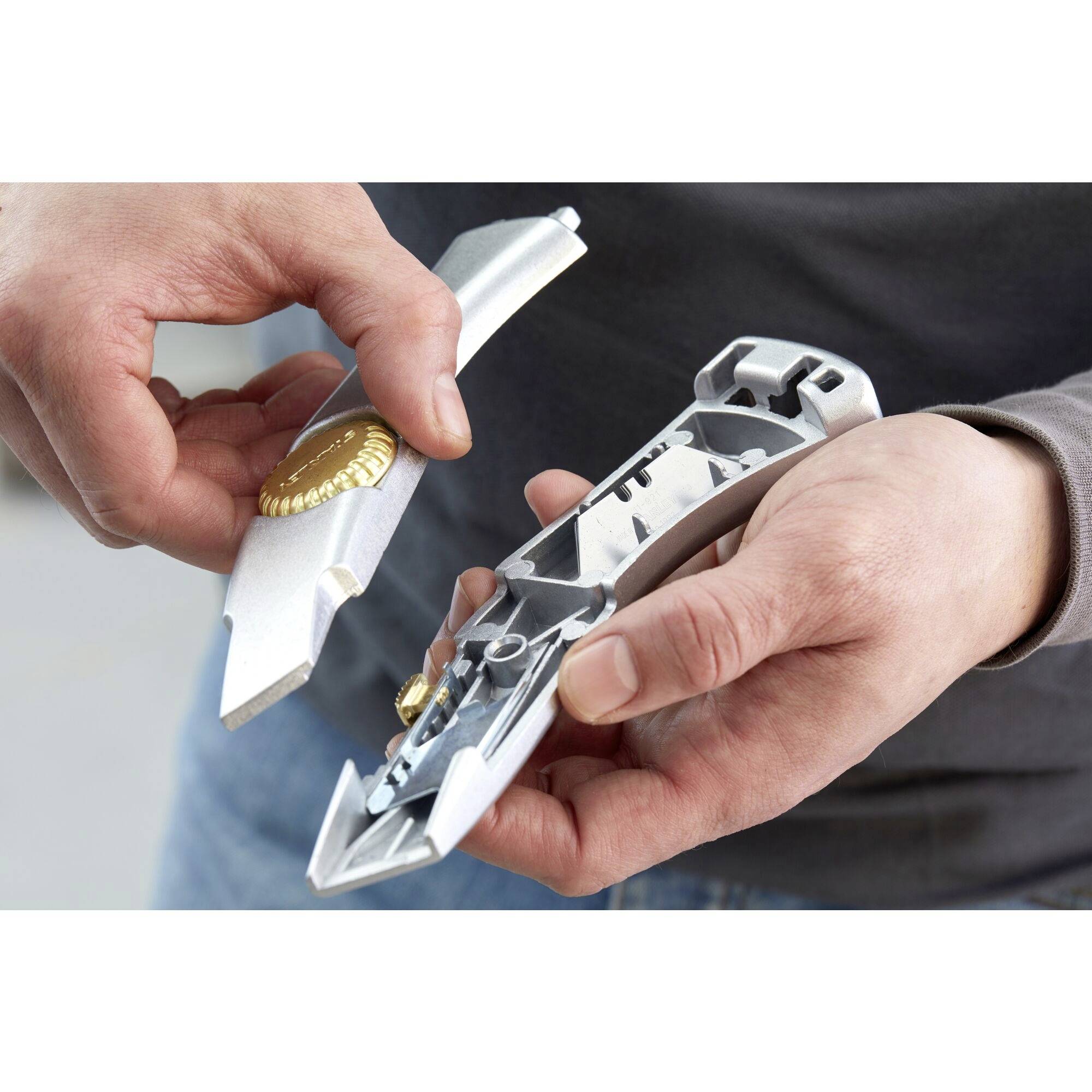 Two hands are holding a silver metal press and a golden beer bottle with a bottle cap opener.