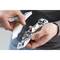 Two hands are holding a silver metal press and a golden beer bottle with a bottle cap opener.