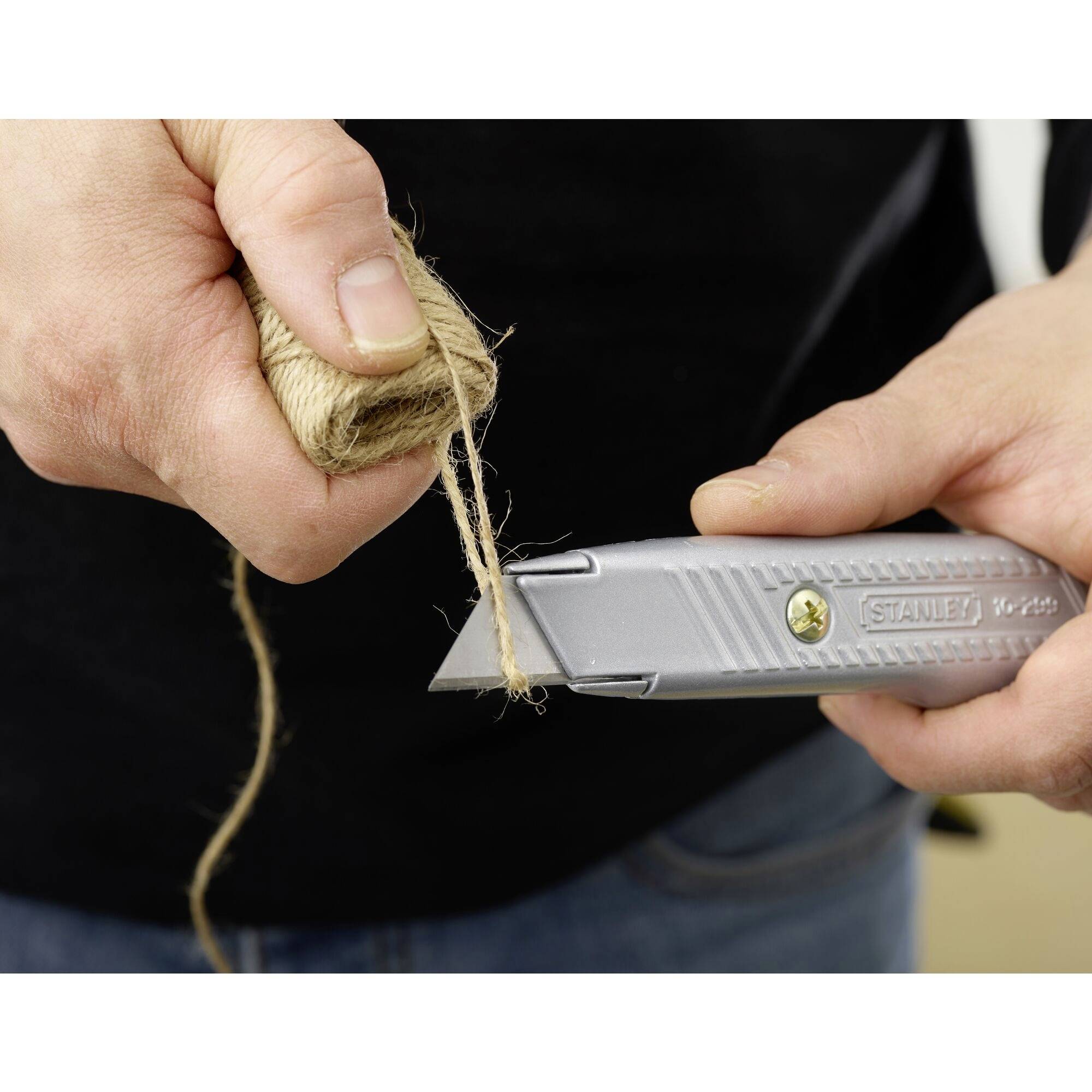 'A person is holding a craft knife and cutting a rope.'