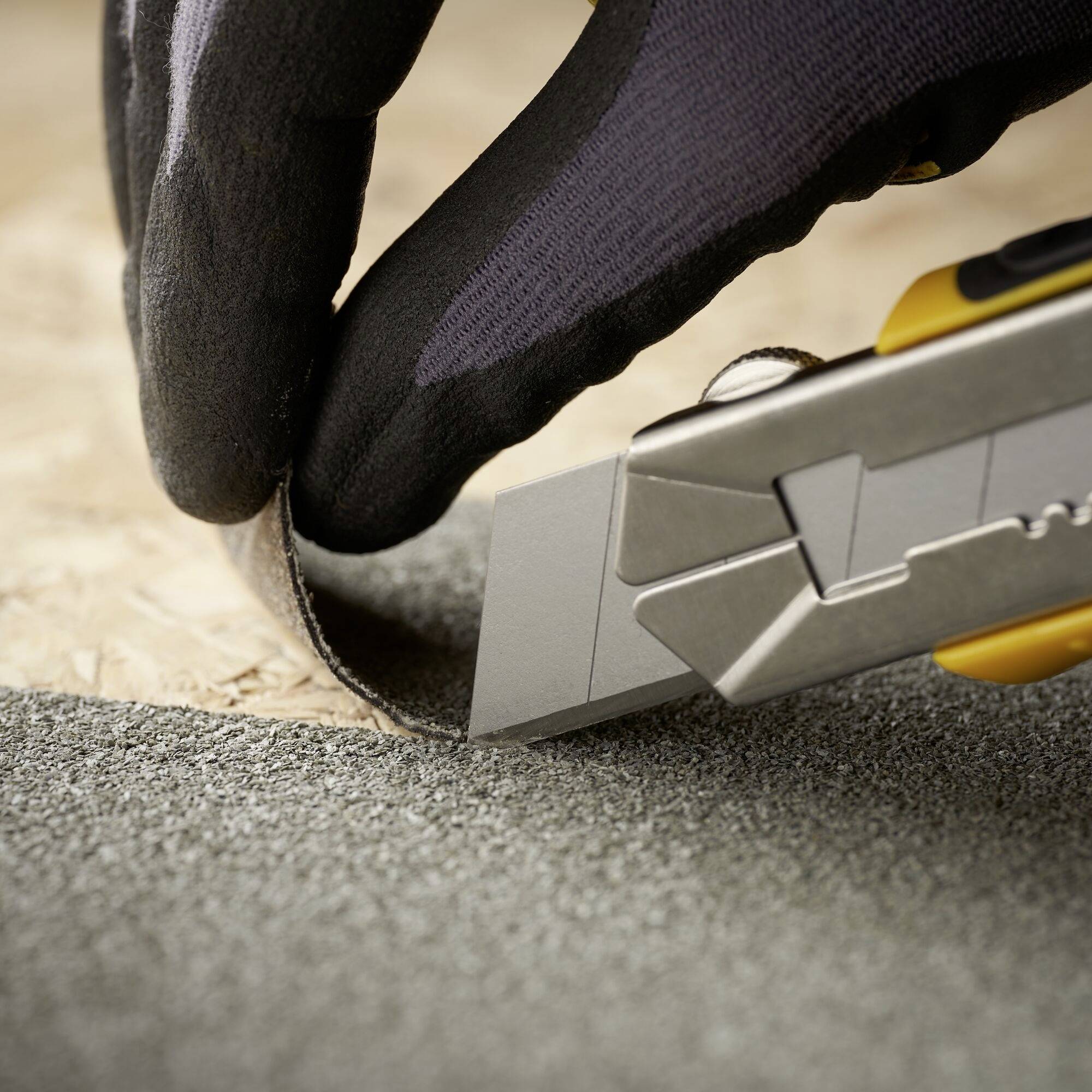 A person is cutting with a craft knife over sandpaper. The focus is on the knife and the precise cutting work.