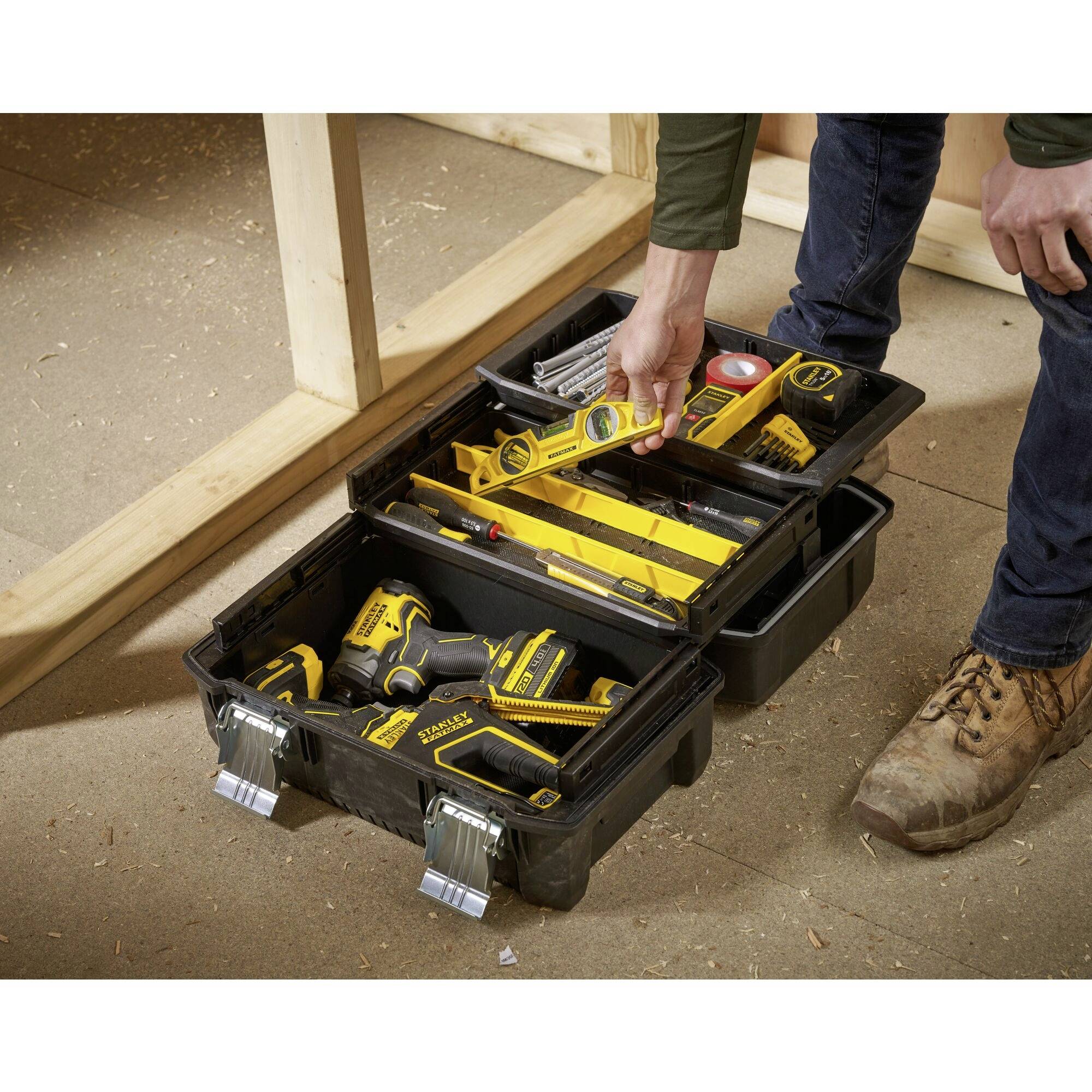 An open toolbox on a wooden floor, filled with screwdrivers, tape measure, drill and other tools.