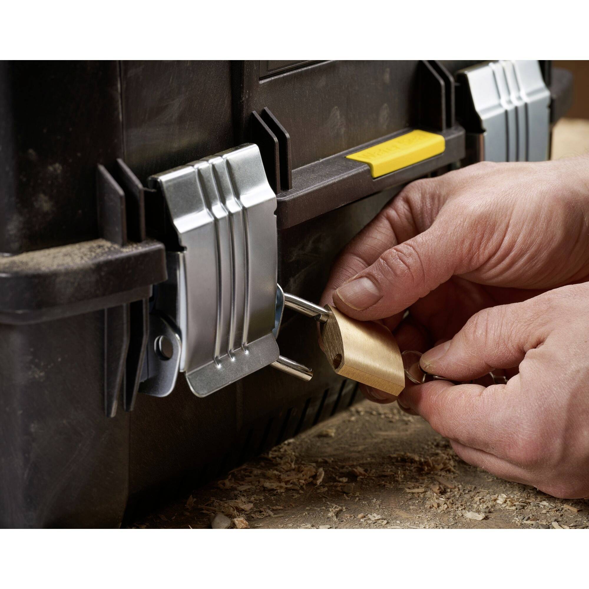 Hands securing a padlock on a toolbox.
