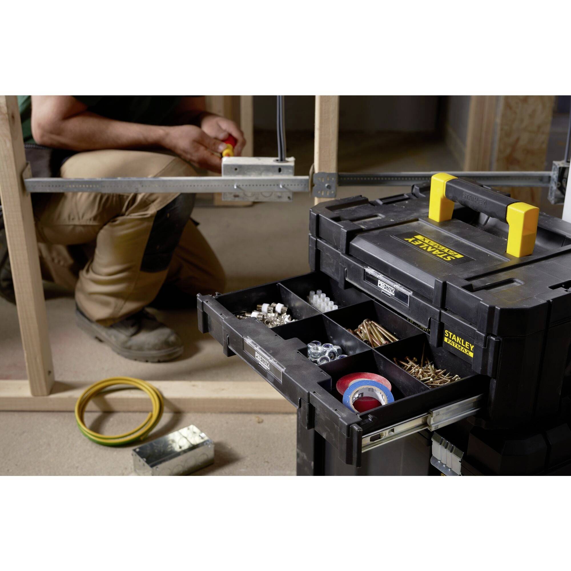 A tradesman is installing wooden frames, with an open toolbox containing screws and tools in the foreground.