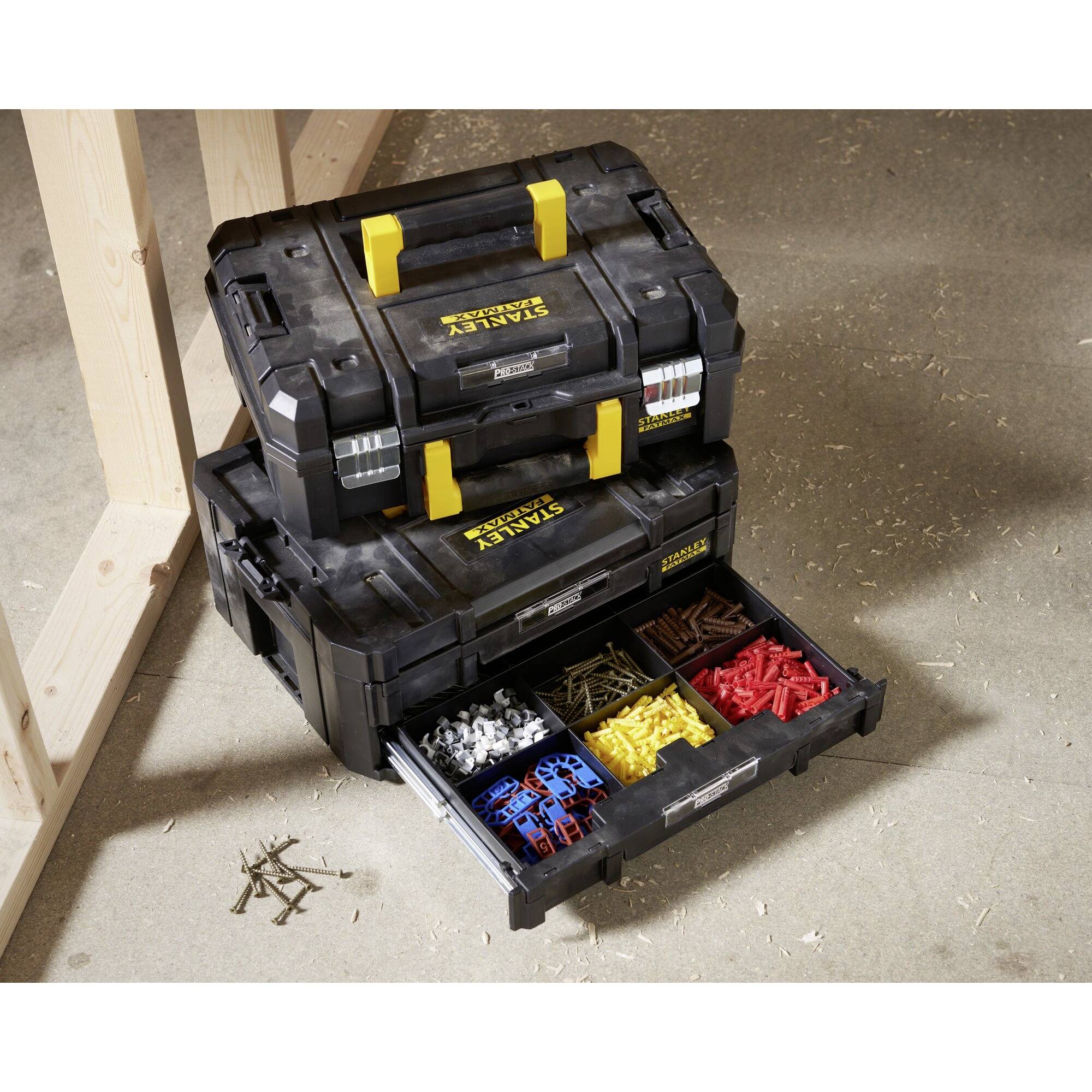 Two toolboxes with open drawers display various screws and wall plugs in compartments. One toolbox is stacked on top of the other.