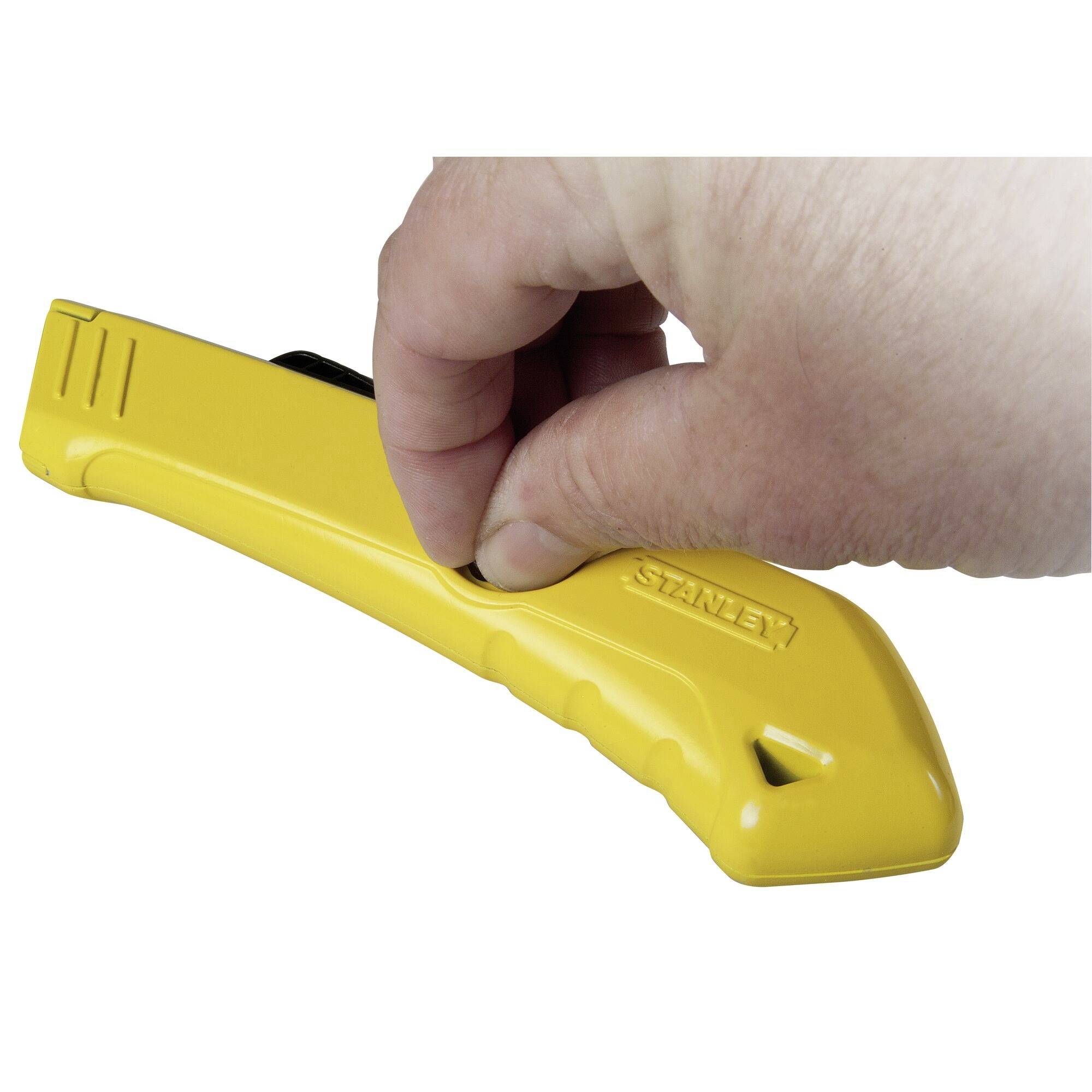 A person is holding a yellow utility knife with their thumb on the sliding mechanism.