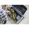 A person is holding an open toolbox with various tools and screws. The person appears to be speaking on the telephone.