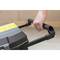 A hand pulls the handle of a black plastic box with a yellow lid in a room.