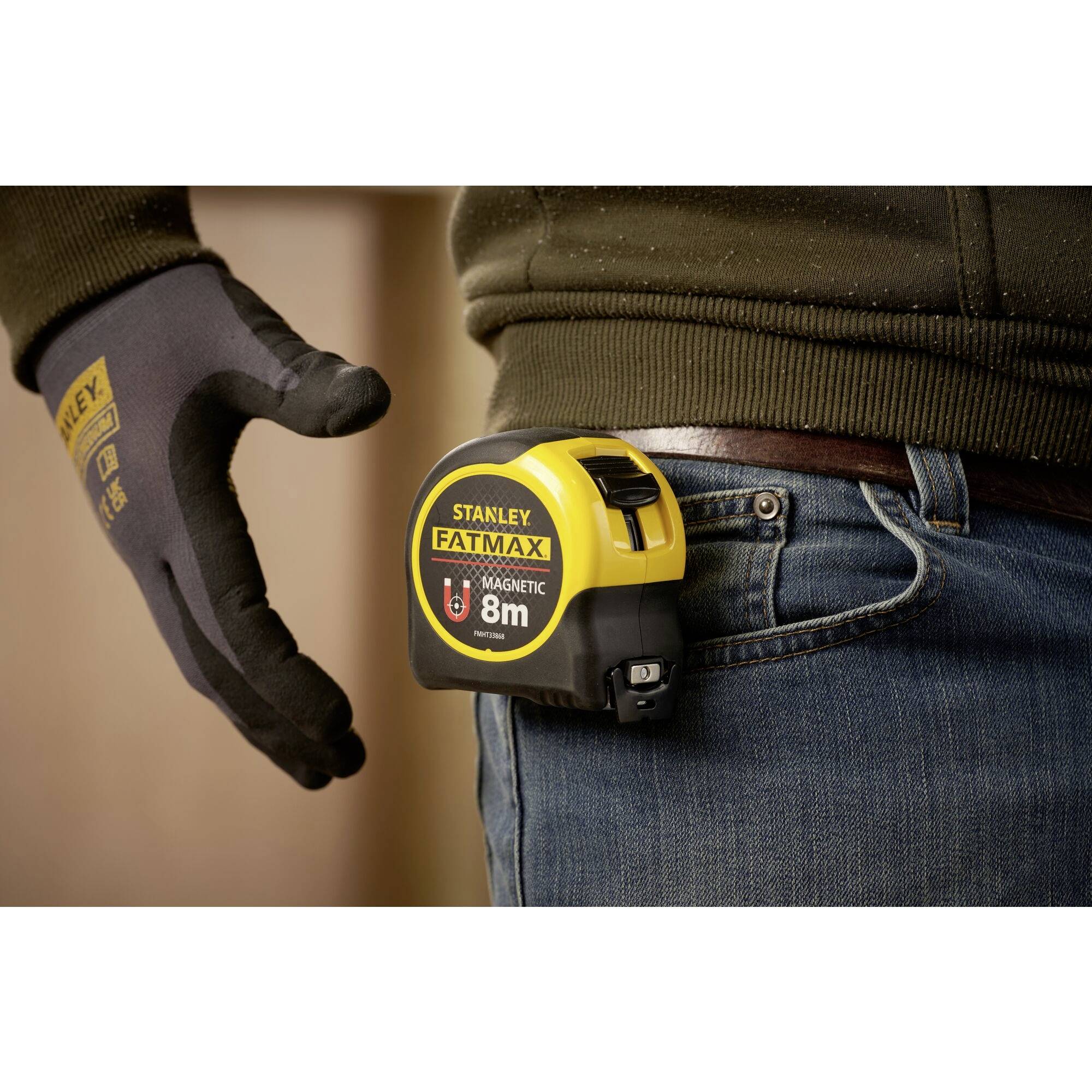 A person is wearing a tape measure on their belt. The tape measure is yellow and black, with the inscription 'Stanley Fatmax 8m'.