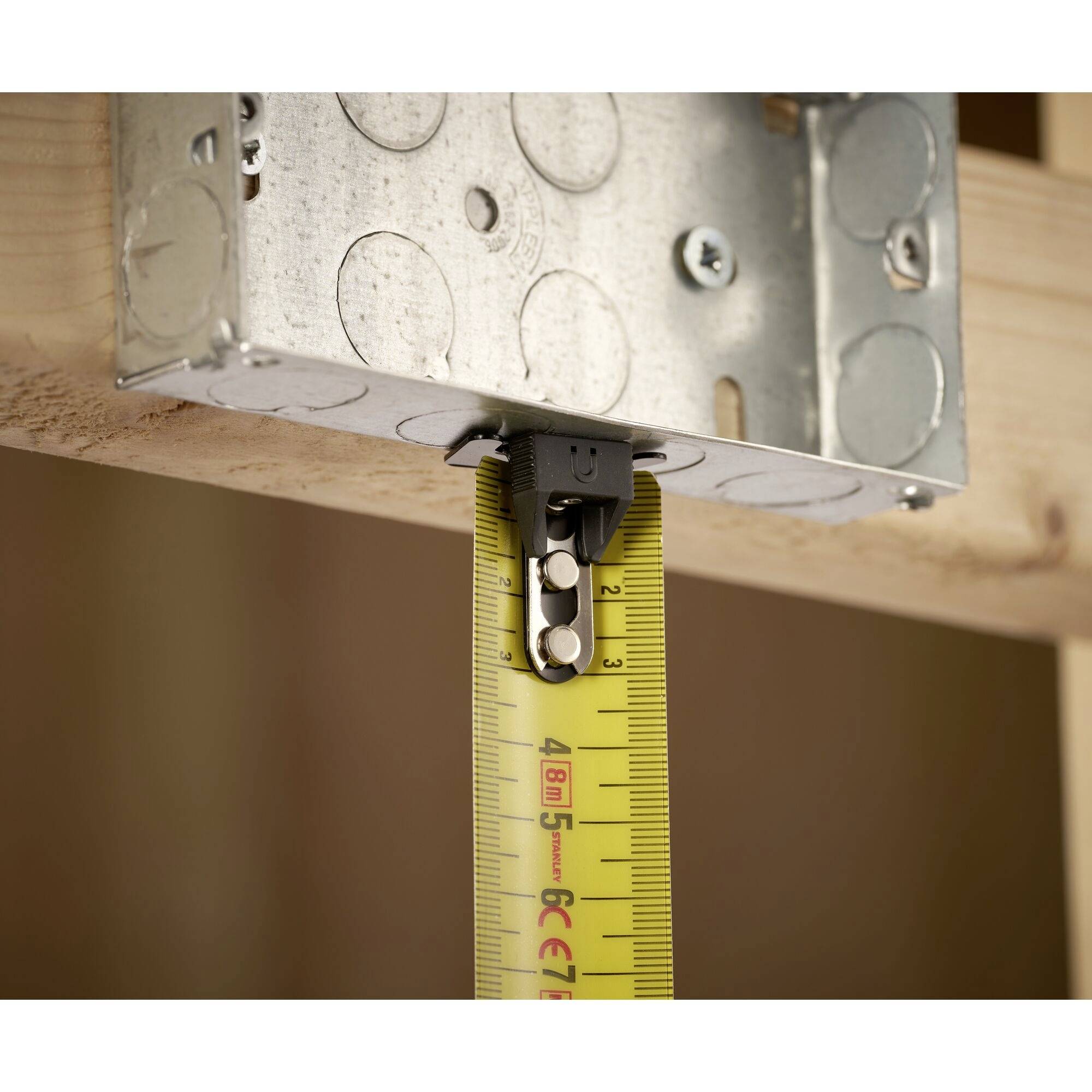 A tape measure is attached to a metal box, indicating a result of approximately 30.5 cm. The box is mounted on a wooden frame.