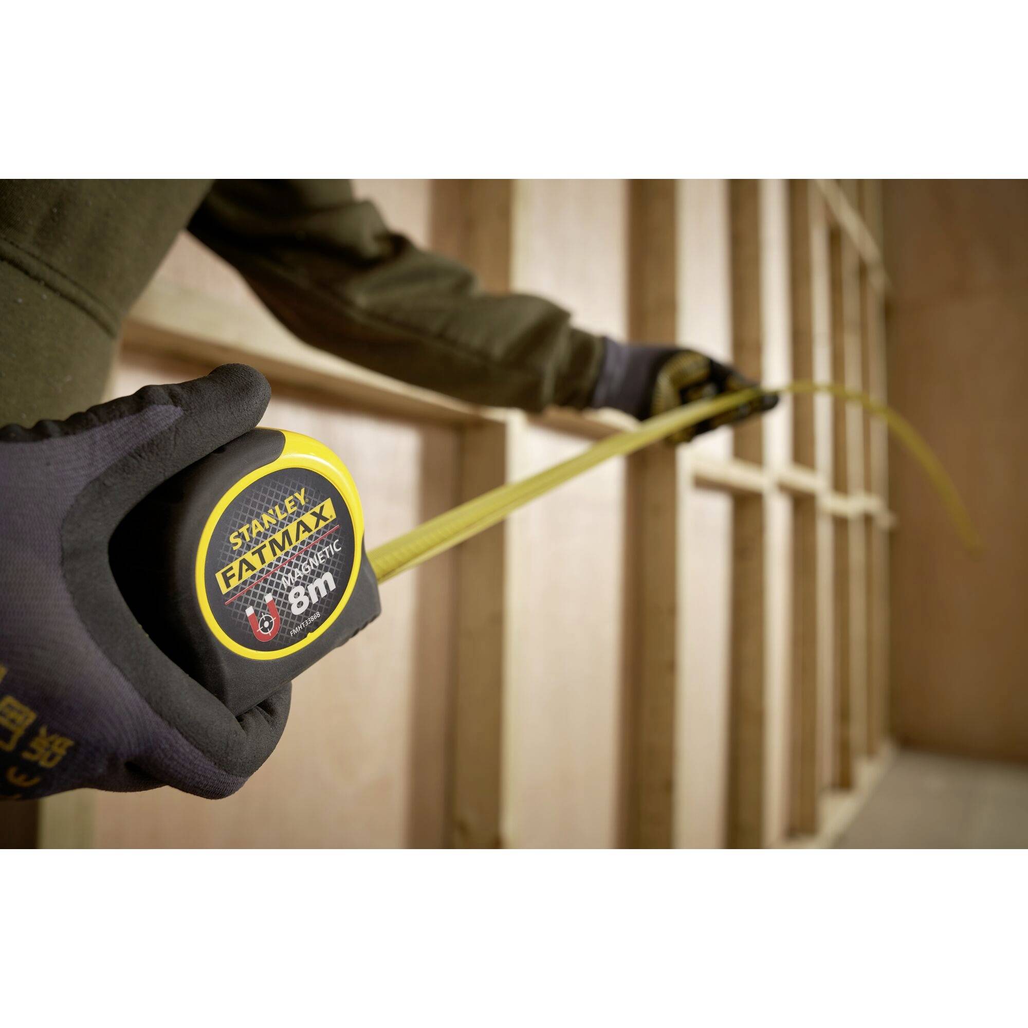 A person is holding an unrolled tape measure against a wooden frame, presumably to carry out measurements or construction work.