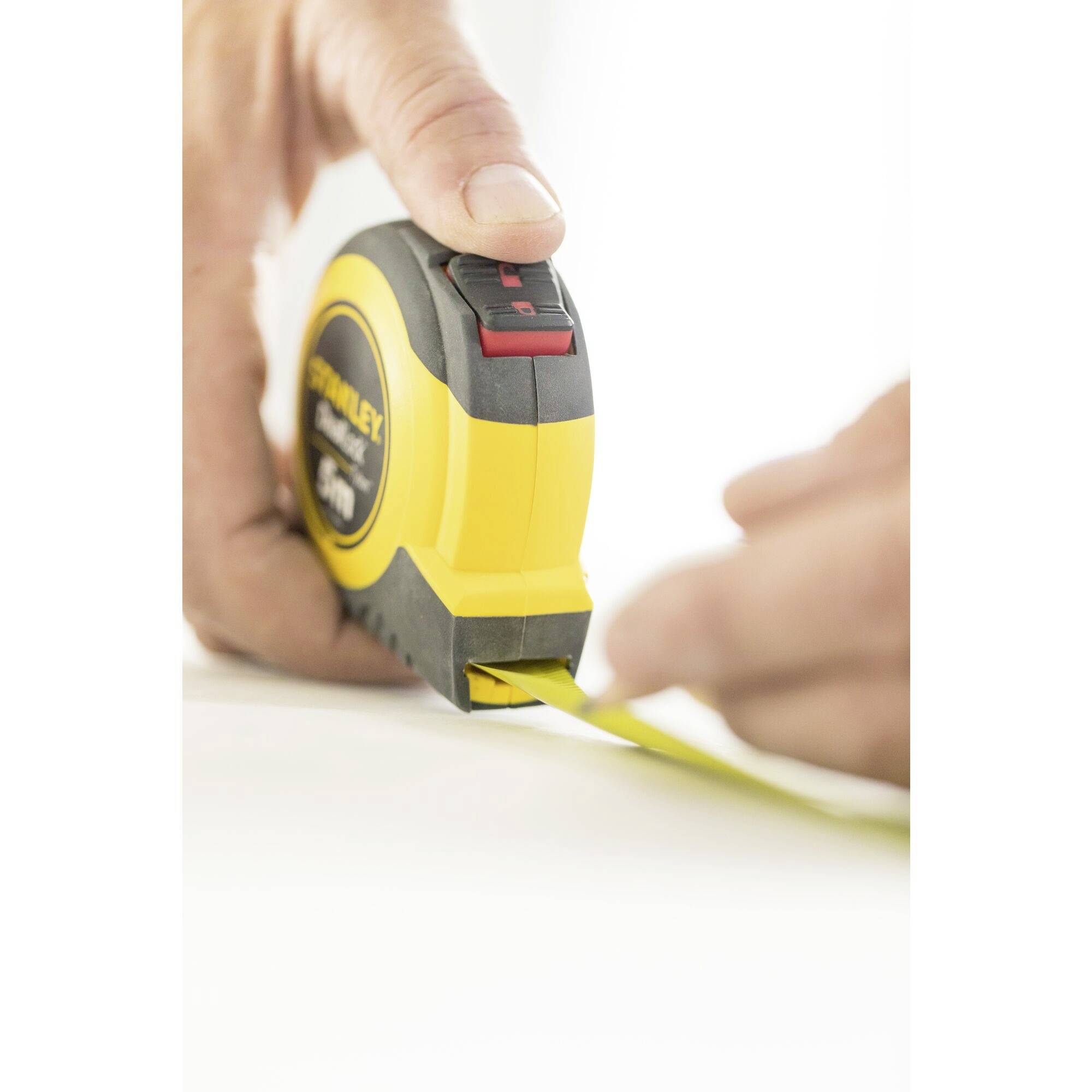 A hand pulls out a yellow tape measure, presumably for measuring length.