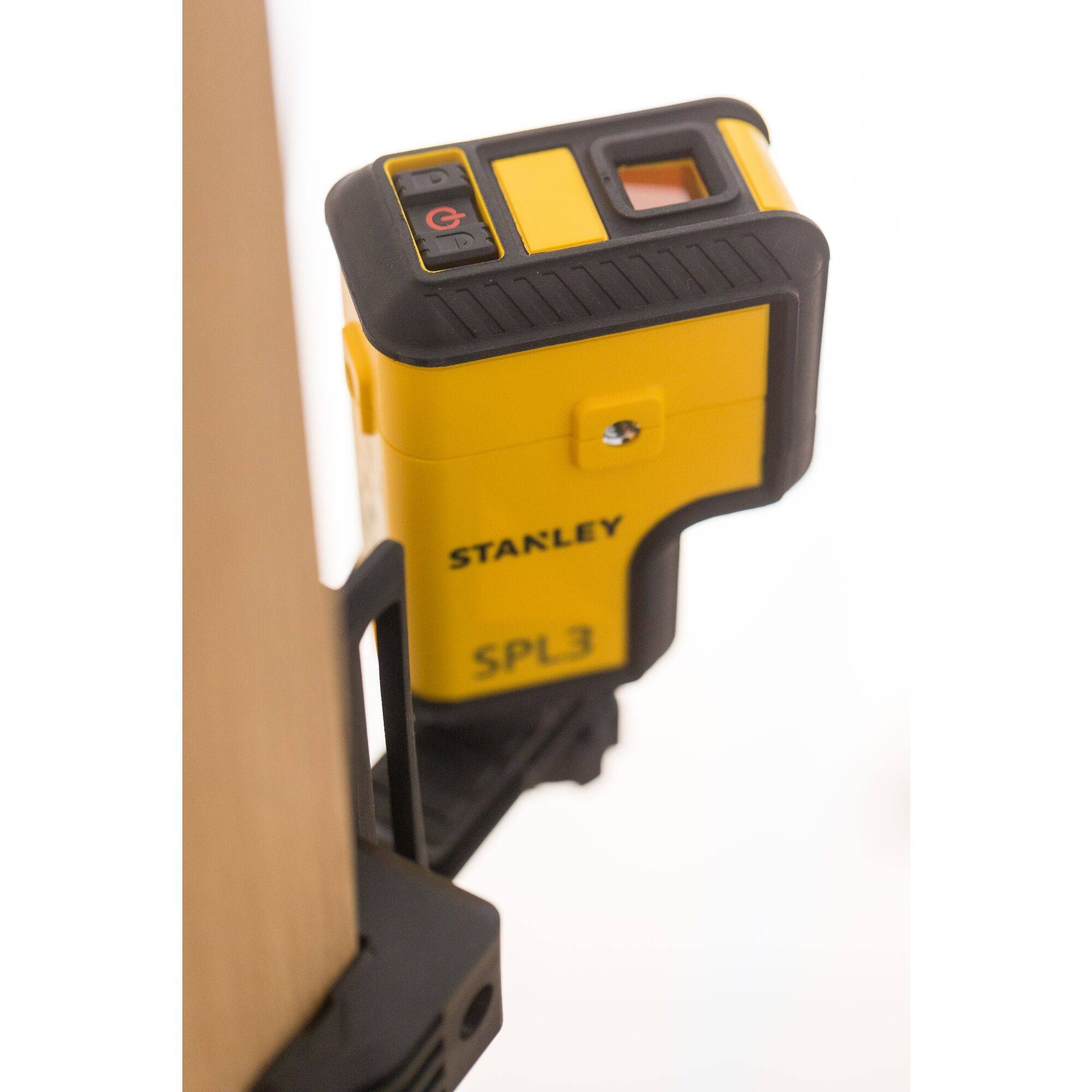 A yellow Stanley laser measuring device, model SPL3, is attached to a wooden beam and is used for precise alignment and measurement.