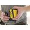 A person is holding a yellow, hand-operated tool with safety and CE markings. They are wearing a grey T-shirt.