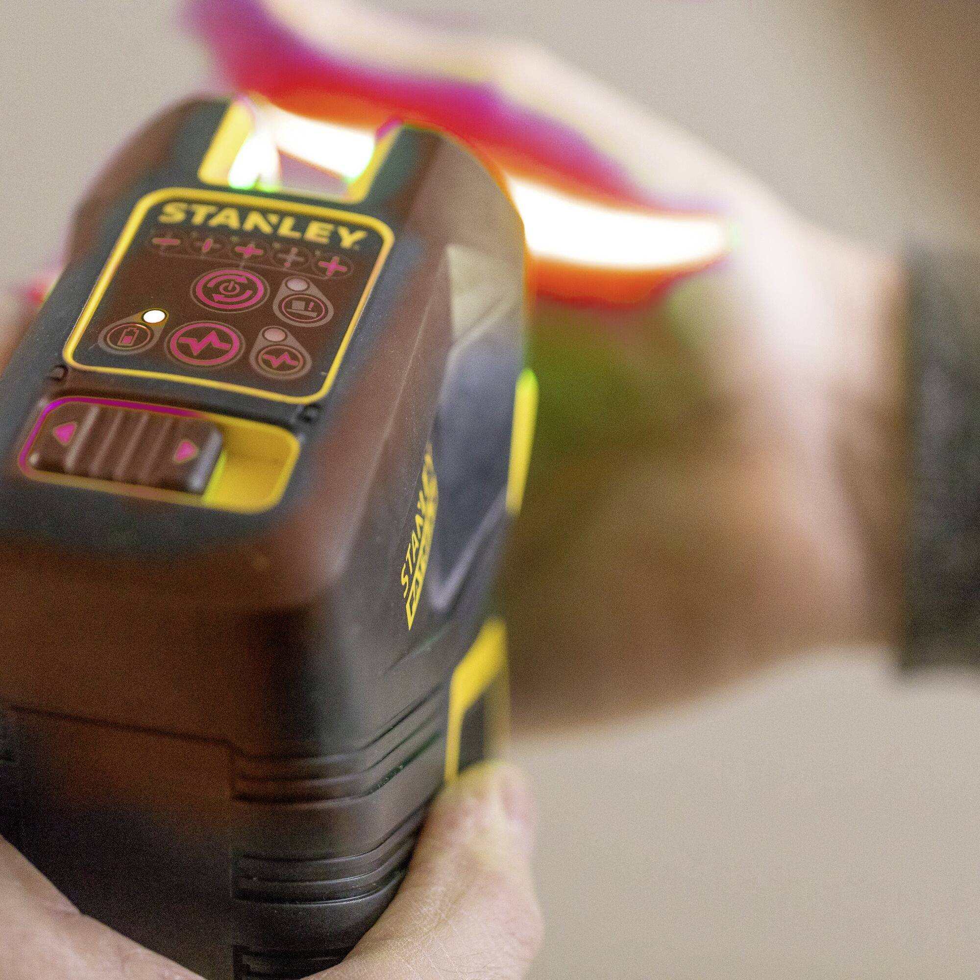A tradesman is using a Stanley laser level device, which is being used for levelling on a construction site.
