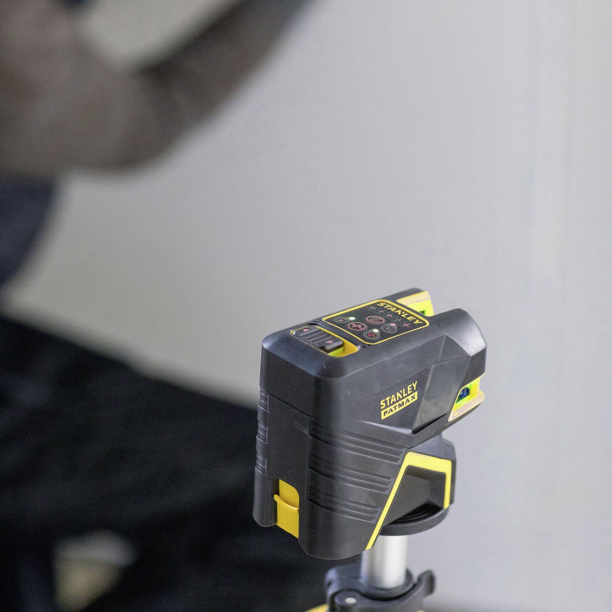 A laser level device on a tripod in a room, likely during construction or renovation work.