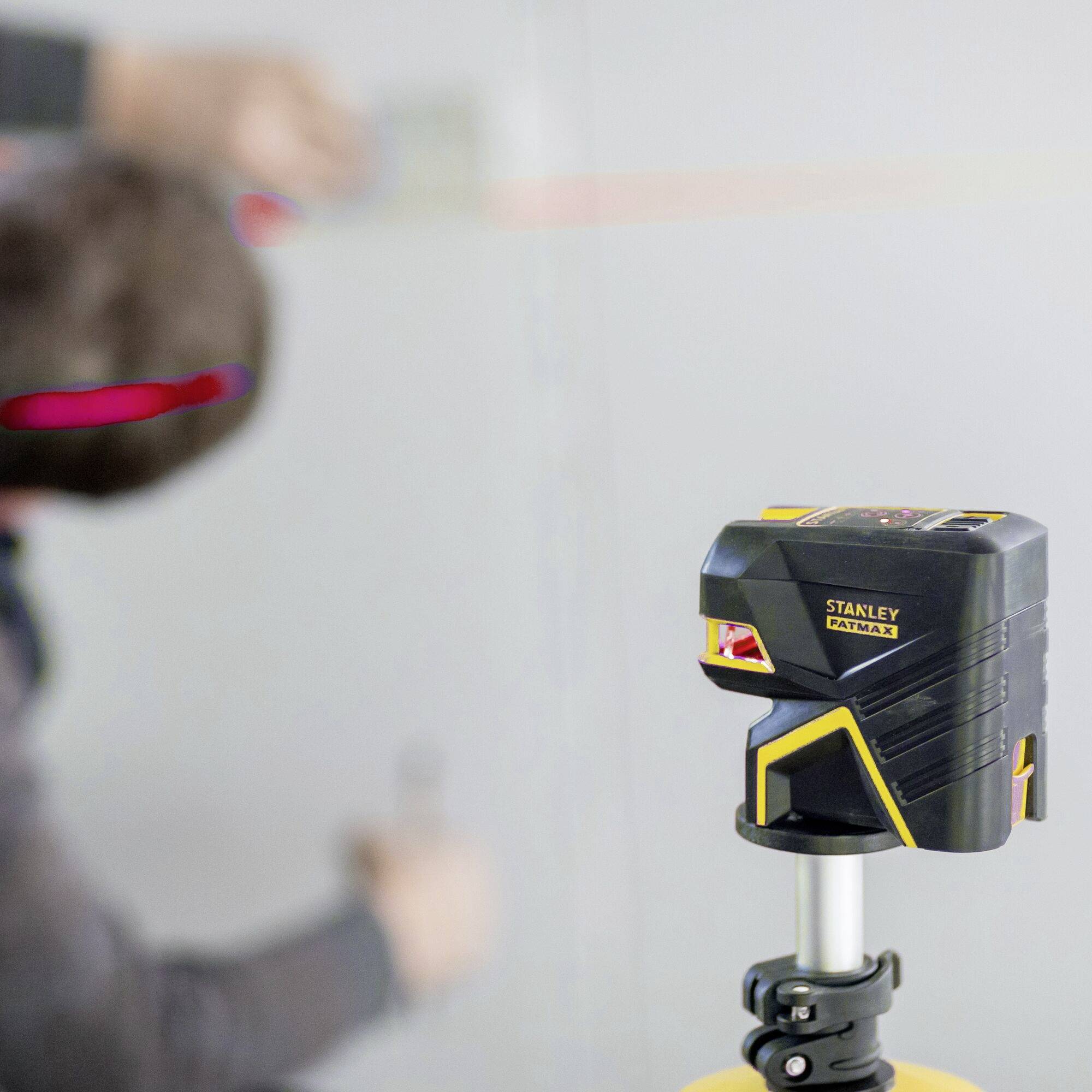 A person is using a laser spirit level device for precise alignment on a wall.