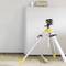 A laser levelling device is mounted on a tripod in a room, projecting a horizontal red line onto the wall for precision measurements.