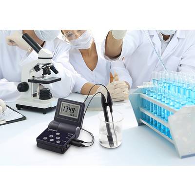 Scientists are working in the laboratory with microscopes and test tubes. In the foreground, a pH meter displays the value 13.49.