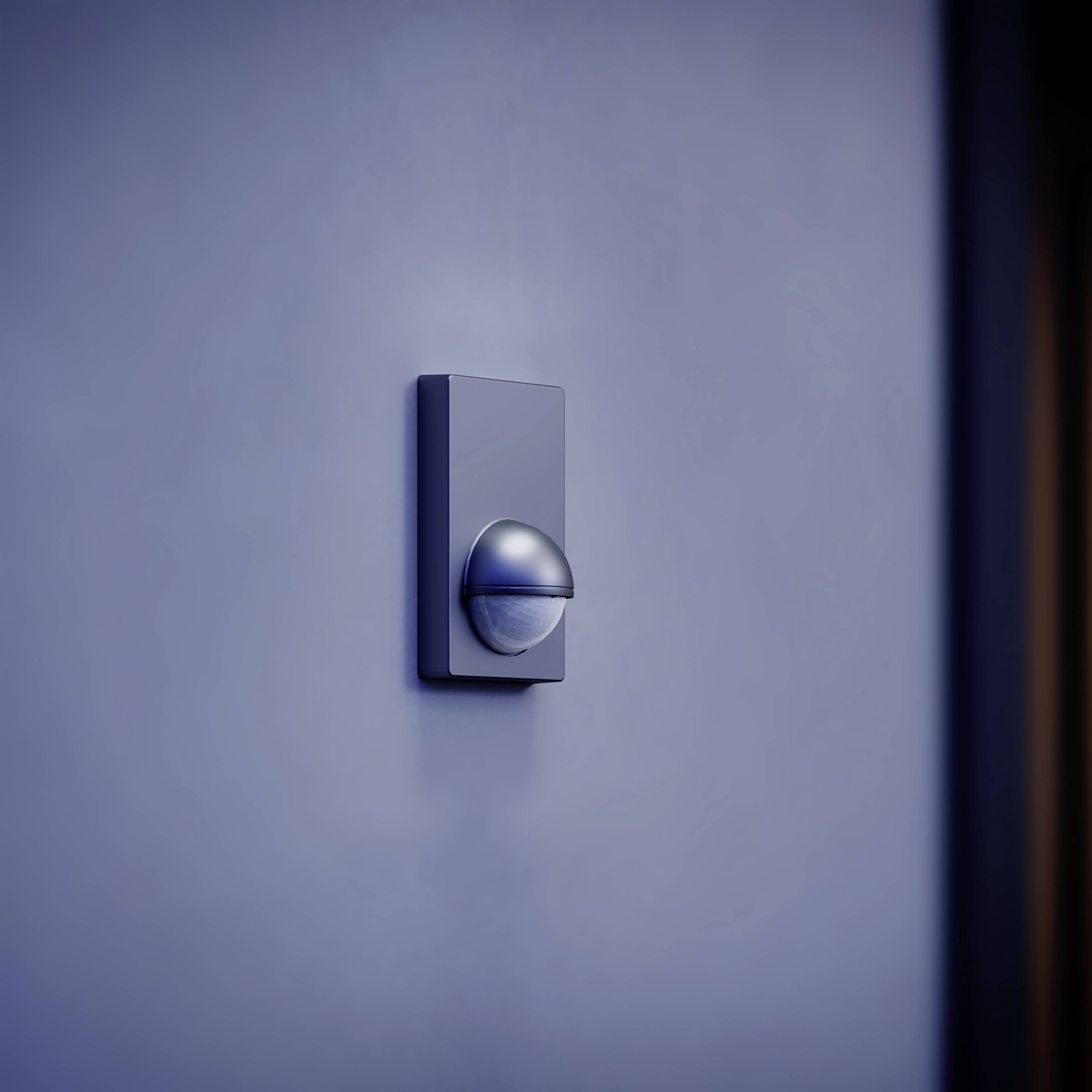 A contemporary, round wall light illuminates a deep navy wall, casting a soft downward glow.