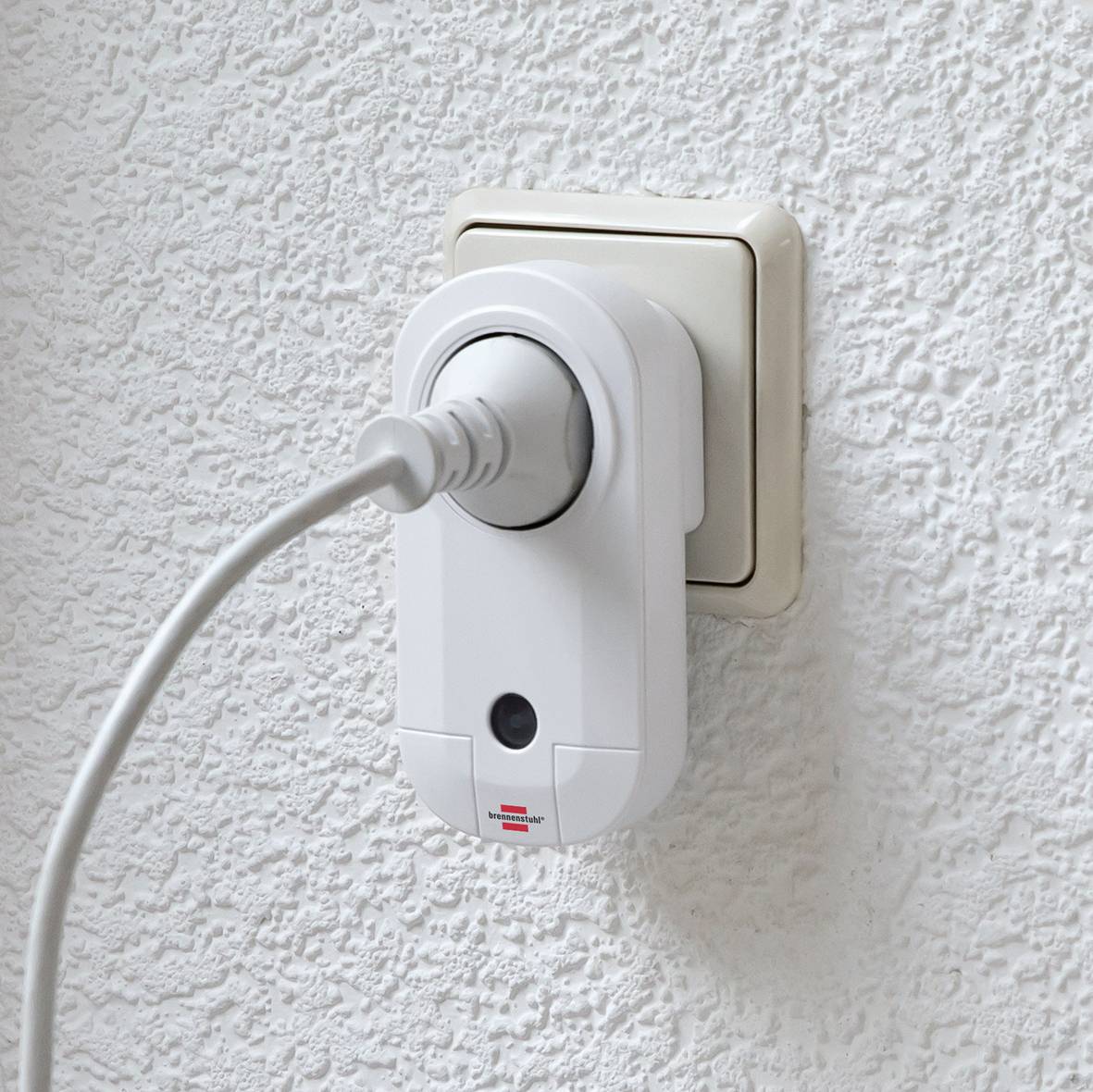 A plug socket with a plug inserted and surge protection on a white wall.