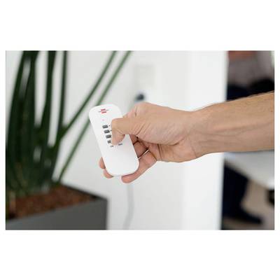 A hand holds a small white remote control with indicator lights and an on/off switch.