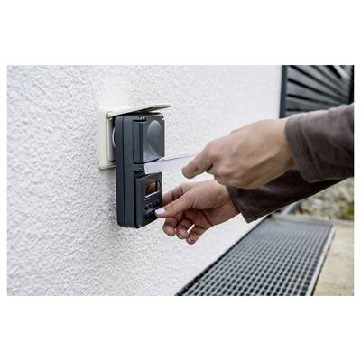 Person swipes a card at an exterior wall-mounted access control keypad to unlock a door or gate.<br>