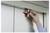 Hand using a red multi-functional key tool on a metallic surface, possibly a utility panel or equipment.