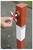 A hand uses a cross-shaped key to unlock a red and white bollard on a paved surface.