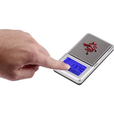A hand presses down on a digital scale weighing small red nails. The display shows '137.0'.