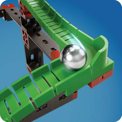 Section of a marble run with a green zigzag path, along which a metal ball is rolling. Structure made of red and black building blocks.