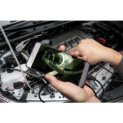 A person is holding a smartphone over an open bonnet and displaying an image of a part of the engine on the screen.