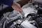 A hand tightens a screw in a car's engine bay using a spanner. It depicts maintenance or repair work.