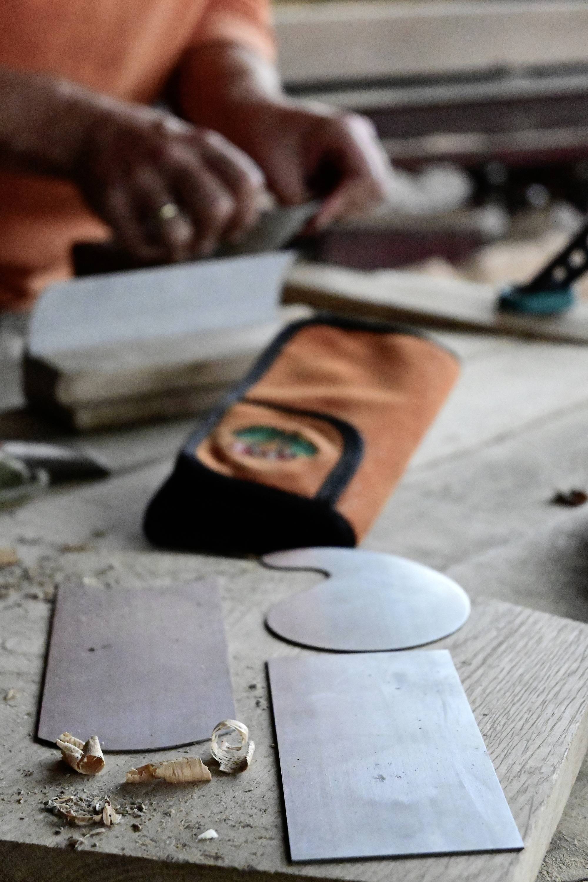 A person is working with wood surface tools on a table; various sanding and polishing tools are laid out in the foreground.