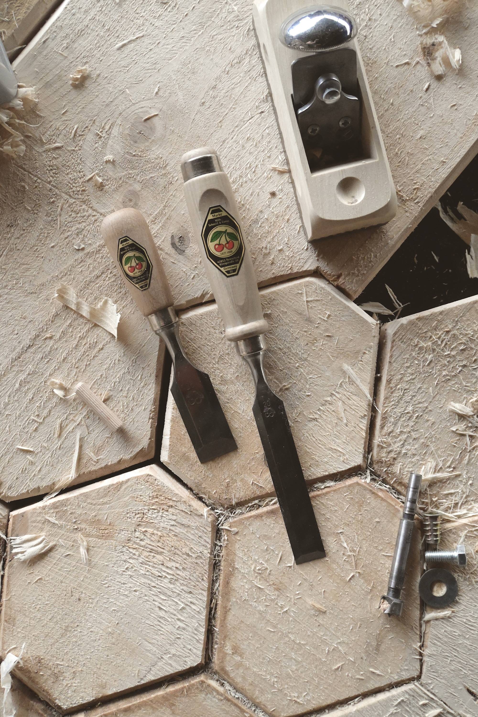Wooden table with carving tools: Two chisels, a plane and a drill on wood with wood shavings.
