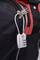 A combination lock is attached to the zip of a black bag with red details.