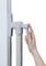 A hand adjusts the lever of a white, vertical pole adjacent to a surface.