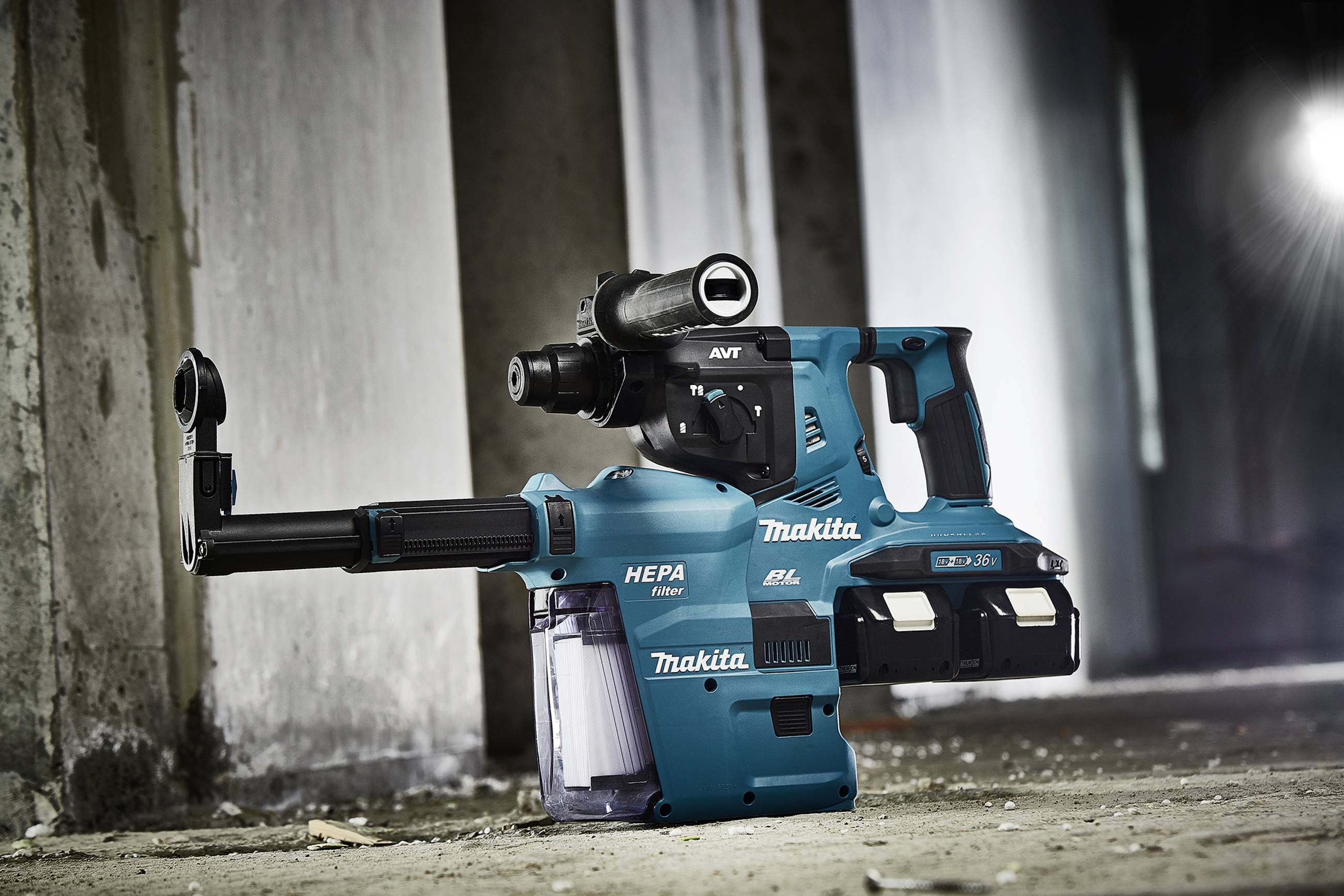 A green Makita hammer drill stands upright in an abandoned building. The device features a HEPA filter system and a robust construction.
