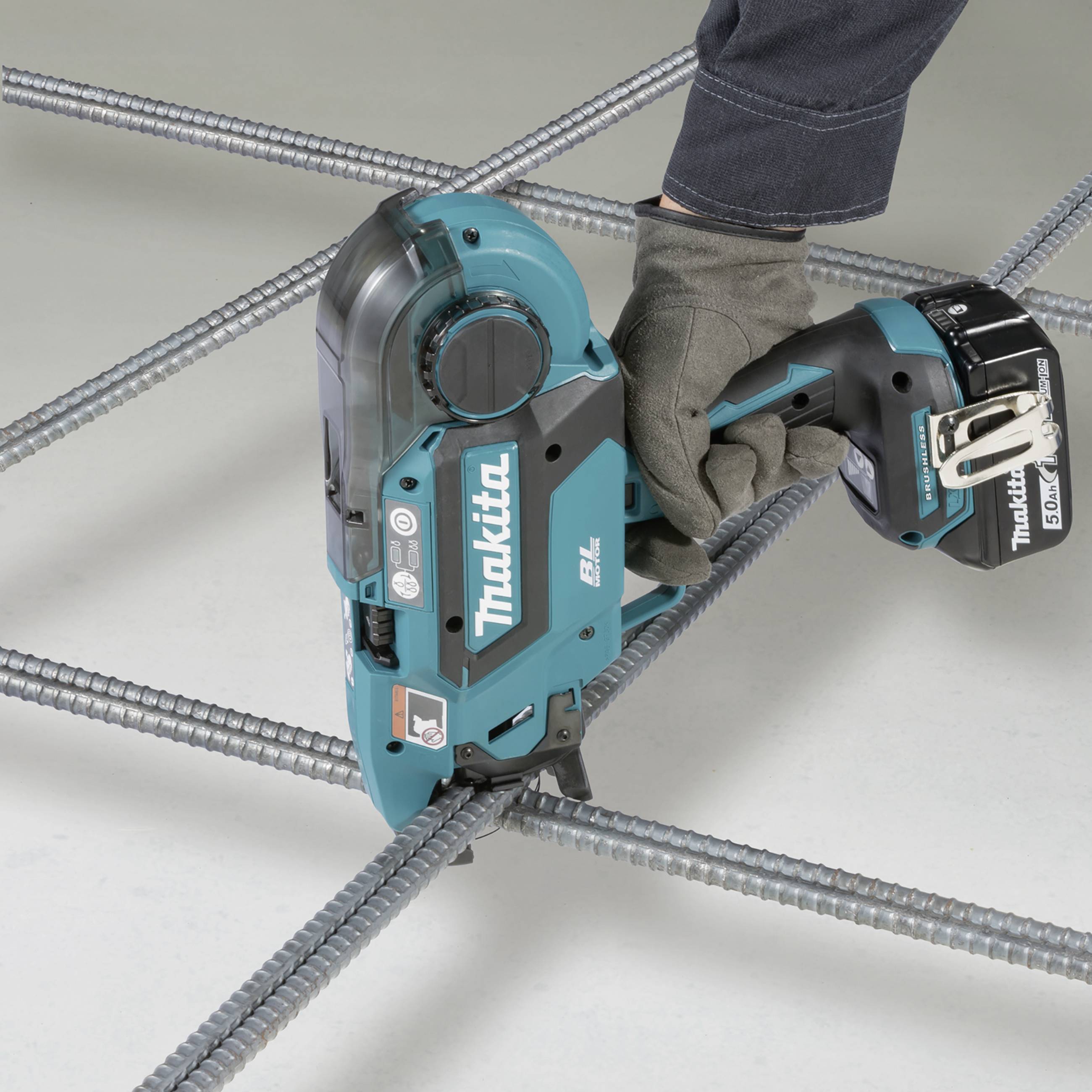 A person is using a blue, battery-powered tool to join steel rods together. The device is made by Makita.
