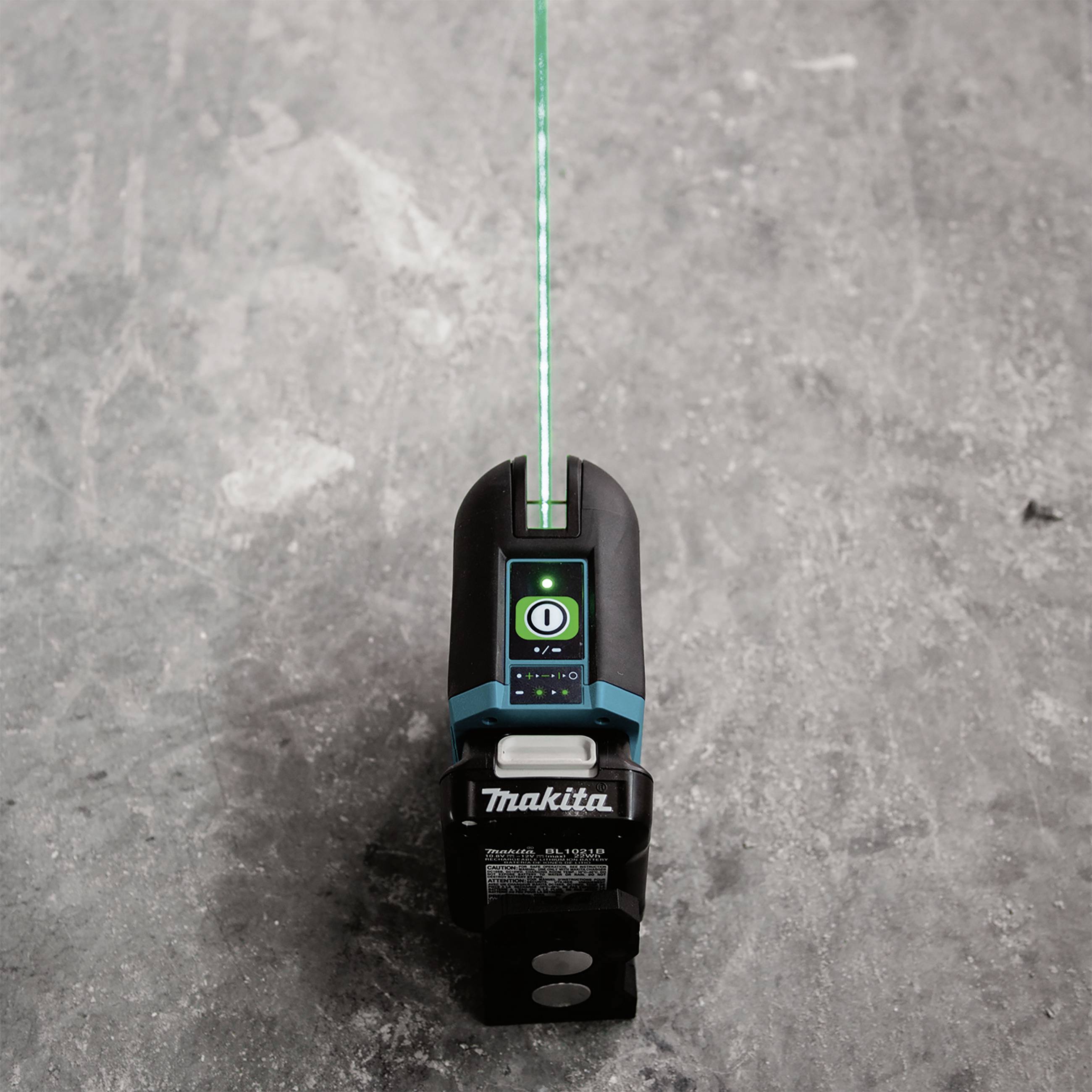 A hand tool on a grey surface, with a green laser line projected onto it.