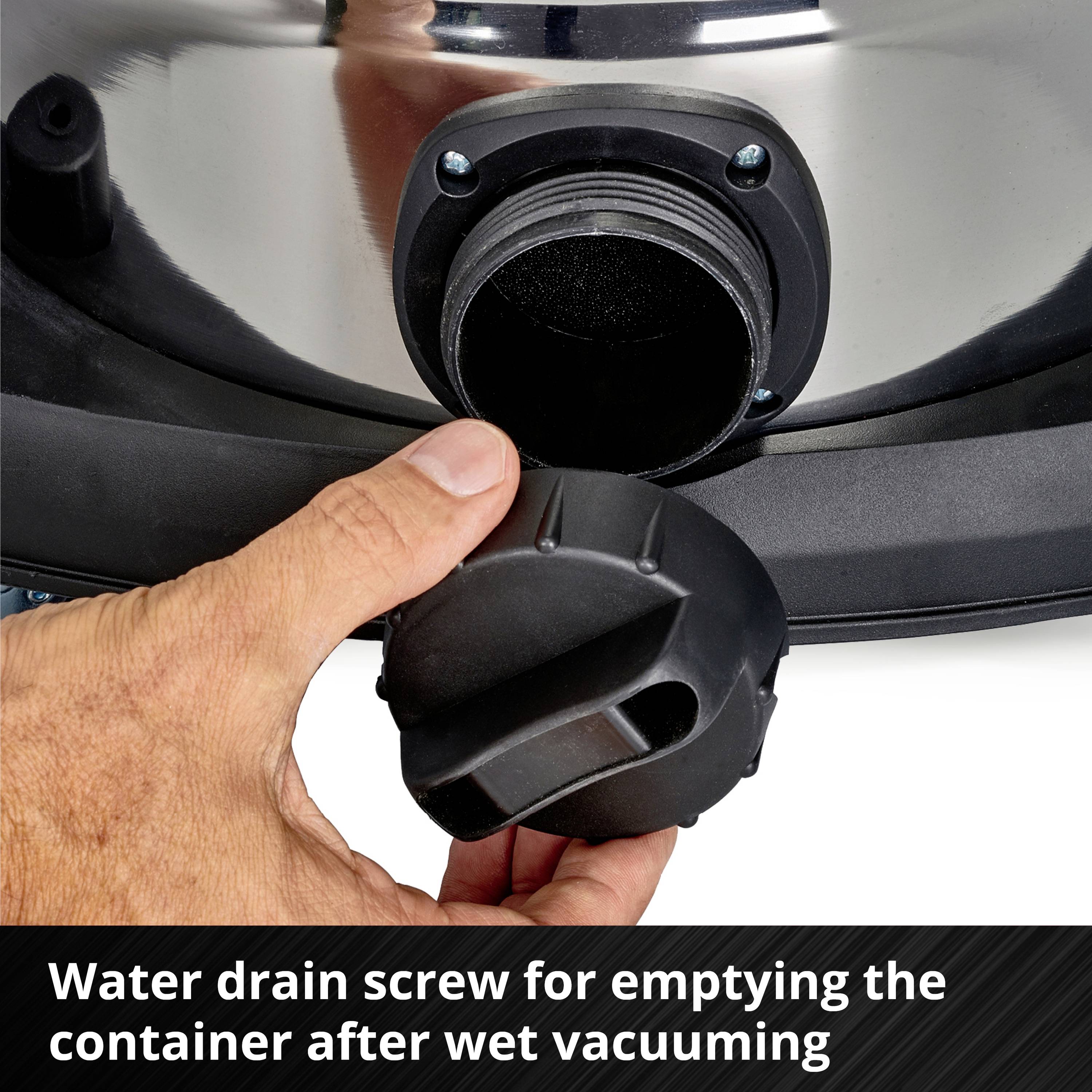 A person is holding a black drain plug to empty water from a wet vacuum cleaner.
