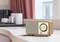 A vintage radio sits switched on a table in a stylish room with red curtains and modern furnishings.