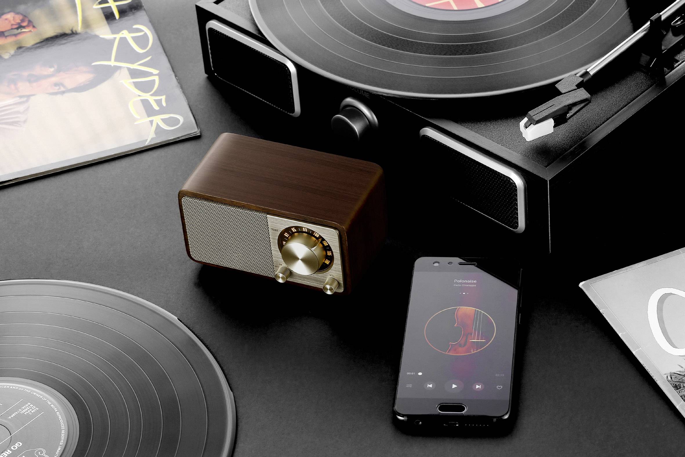 Record player with a vinyl record, alongside a wooden-cased radio and a smartphone. A musical retro atmosphere.