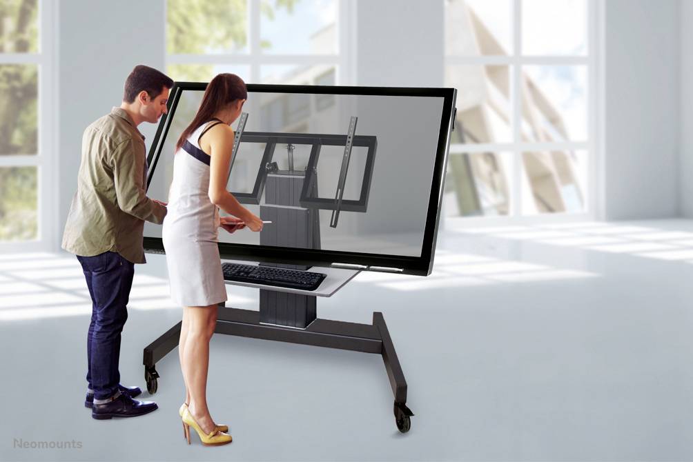 People are interacting with a large touchscreen in a modern, bright room. They are studying the display attentively.
