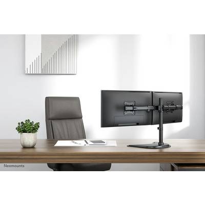 A modern office with a dark wooden desk, an empty leather chair, a dual monitor mount for two screens, and a small plant pot.