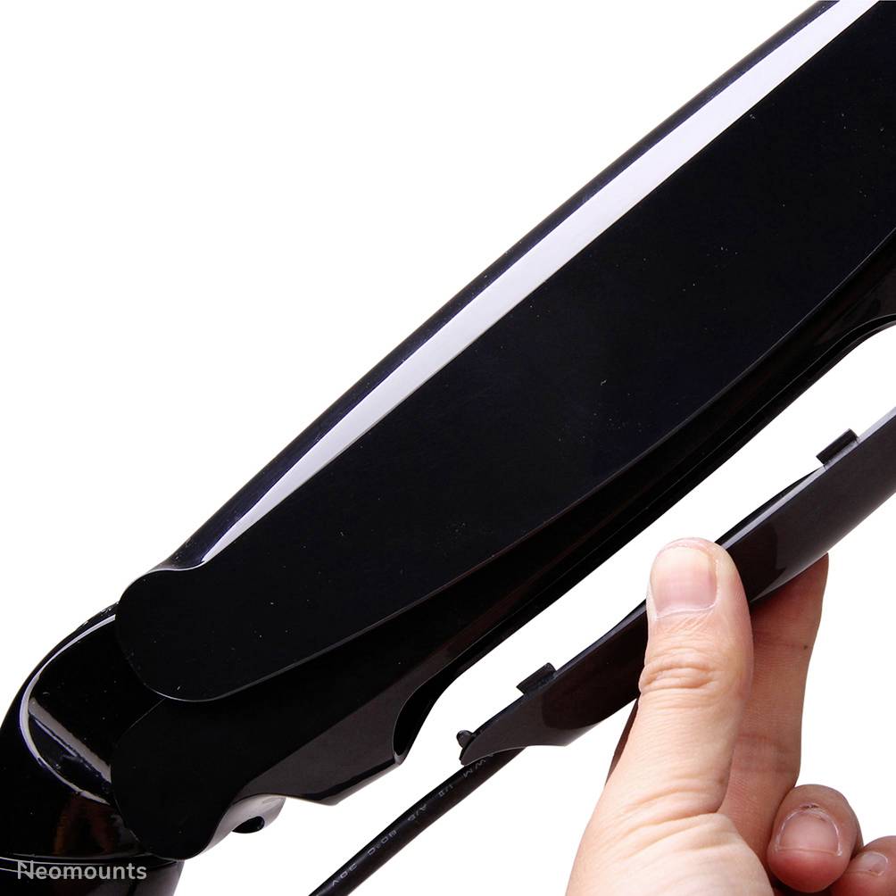 Close-up of a hand adjusting a monitor mount. The mount is black and ergonomically shaped.